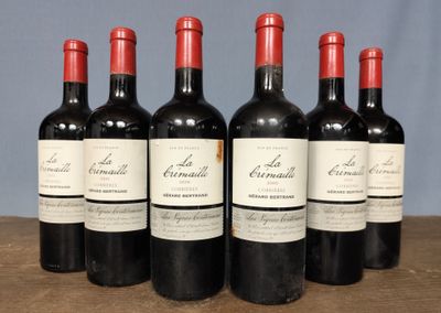 six bottles of red wine are lined up on a wooden table