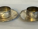 une paire de tasses et soucoupes plaquées argent posées sur un fond blanc