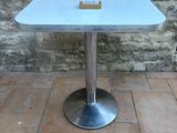 a white table with a glass top on a brick floor
