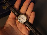 a person holding a wrist watch in their hand