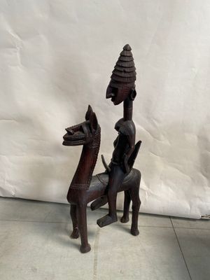 statue en bois représentant un homme à cheval, avec un oiseau sur le dos