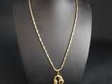 a gold plated necklace with an elephant pendant on a mannequin