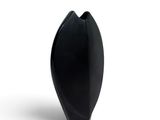 un vase noir posé sur une surface blanche