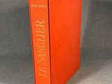 an orange book sitting on top of a table next to a gray wall