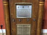 an old radio sitting on top of a carpeted floor next to a red wall
