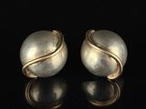 deux boucles d'oreilles en argent et en or sur un fond noir