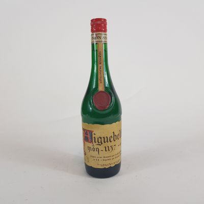 une petite bouteille d'alcool posée sur une surface blanche, avec un bouchon rouge