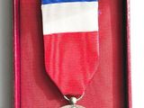 red, white, and blue medal in a red box on a white surface