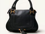 the black leather handbag has gold hardware on the handles