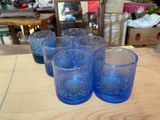six blue glasses sitting on a table with a mirror in the background
