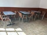 Des tables et des chaises sont alignées dans une pièce aux murs marron.