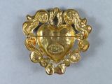 a gold brooch with a heart and birds on it