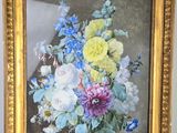 tableau représentant un bouquet de fleurs dans un cadre doré posé sur une table
