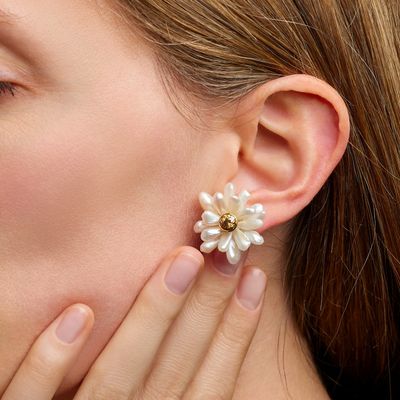 La femme porte une paire de boucles d'oreilles ornées de fleurs.