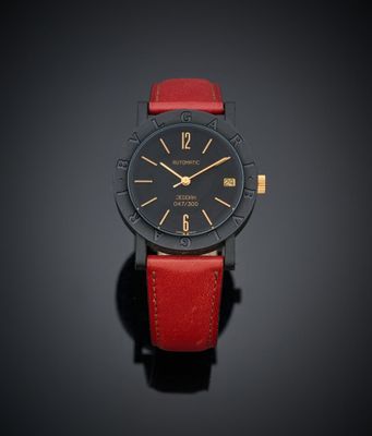 un gros plan d'une montre noire et rouge posée sur une surface noire