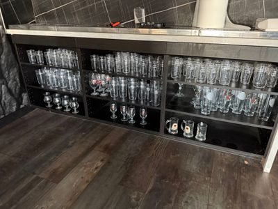 bottles and glasses on a shelf in a room with a tiled wall