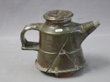 a green tea pot with a lid on a table