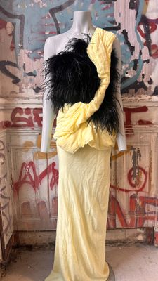 a mannequin wearing a yellow dress with black feathers on it