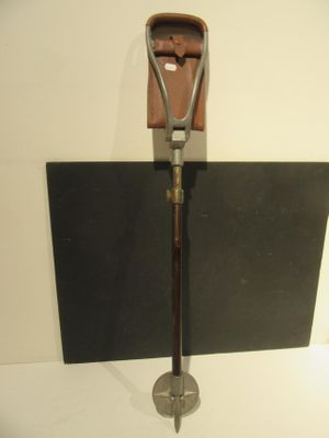 a metal shovel with a leather case on top of it