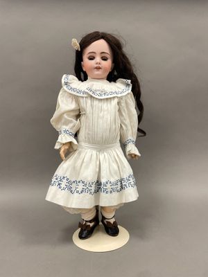 une poupée en porcelaine représentant une petite fille vêtue d'une robe blanche et de chaussures noires