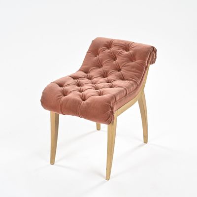 chaise rose avec des pieds en bois et un coussin capitonné, sur fond blanc