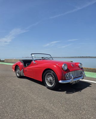 La voiture rouge est garée sur le bord de la route.