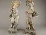 deux statues représentant un garçon et une fille tenant des paniers de fleurs