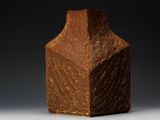 un vase marron posé sur une table sur fond noir