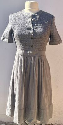 grey dress on a mannequin stand against a white wall