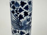 a blue and white vase with a bird and flowers on it