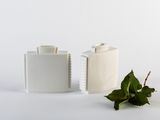 deux vases blancs posés l'un à côté de l'autre sur une surface blanche