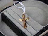 une petite croix en or dans un écrin, accompagnée d'un cordon blanc