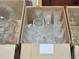 Plusieurs cartons contenant de la verrerie sont empilés sur une table dans une pièce.