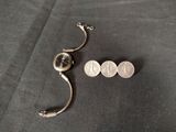 a small silver object on a black surface next to a coin