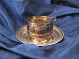 une tasse et une soucoupe en argent posées sur un napperon bleu