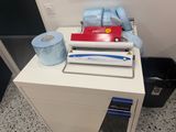 a white desk with a printer and a roll of toilet paper on it