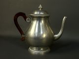 a silver tea pot with a wooden handle on a table