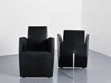 pair of black leather chairs in a white room with a white wall