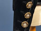 a close up of a black jacket with gold buttons on a mannequin