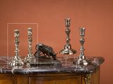 trois bougies en argent posées sur une table au plateau en marbre