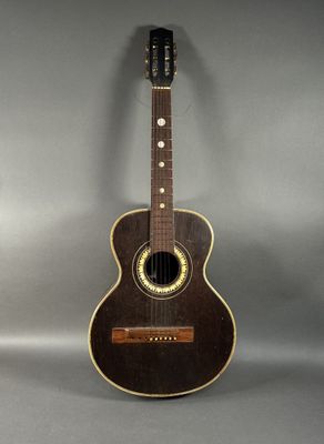 une vieille guitare acoustique posée sur une surface grise