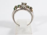 a close up of a silver ring with green and white stones