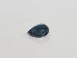 a blue sapphire tear shaped stone on a white surface