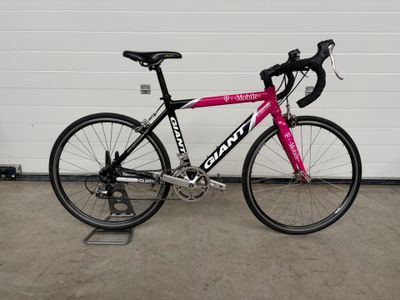 un vélo rose garé devant la porte d'un garage