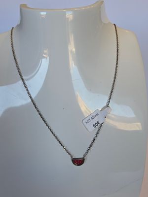 chaîne en argent avec un pendentif en forme de cœur rouge sur un mannequin blanc