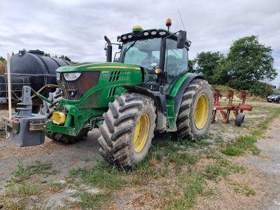 a green tractor that is parked in the dirt