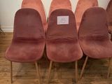 six pink velvet chairs in a row with a sign on the back