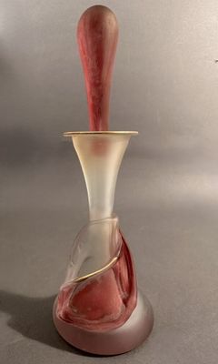 un vase en verre avec une anse rouge posé sur une table