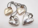 trois clochettes en forme de cœur, en argent et en or, suspendues à un fil
