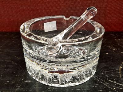 un cendrier en verre contenant une cuillère, posé sur une table